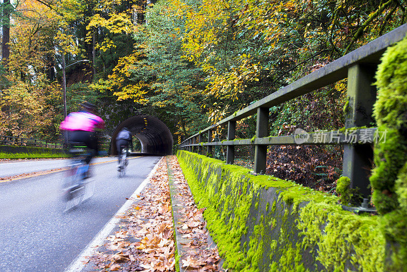 骑自行车的人在秋天的道路上有桥和隧道