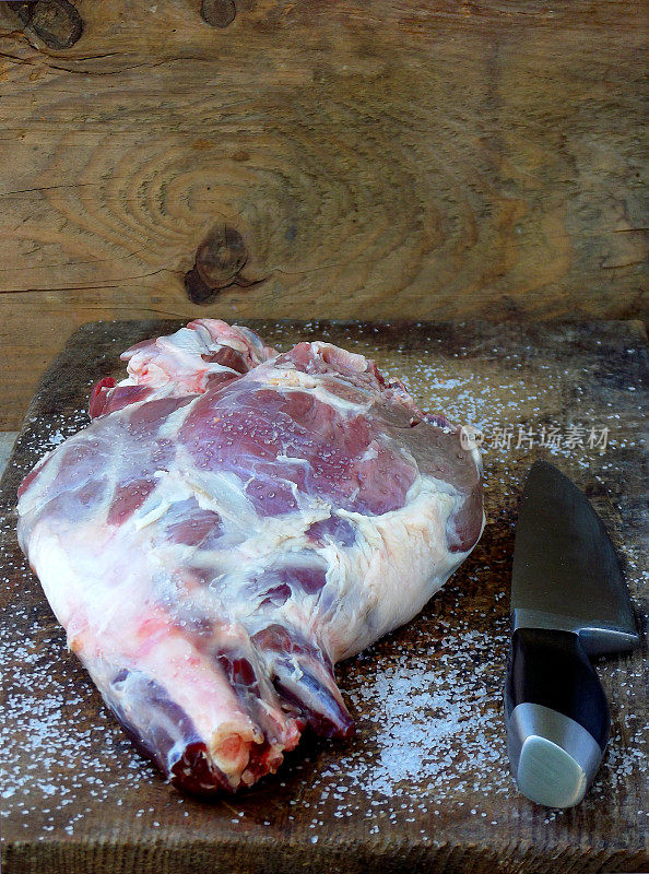 新鲜的生肉。用刀放在木板上的羊腿，用于烤、炖、肉饭、烤肉、烤肉串、什锦饭