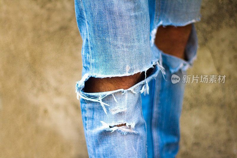 特写的男人的时尚粉碎在膝盖蓝色牛仔裤
