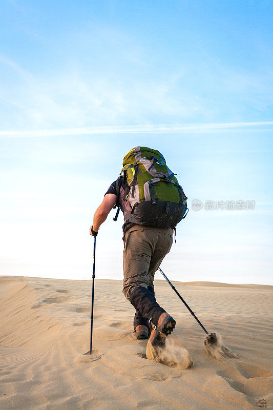 背着背包在沙漠中徒步旅行的男人
