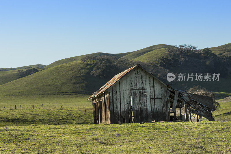 废弃的农场建筑，背景是小山