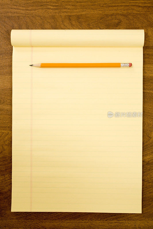 桌上放着空白的黄色划线记事本和铅笔。