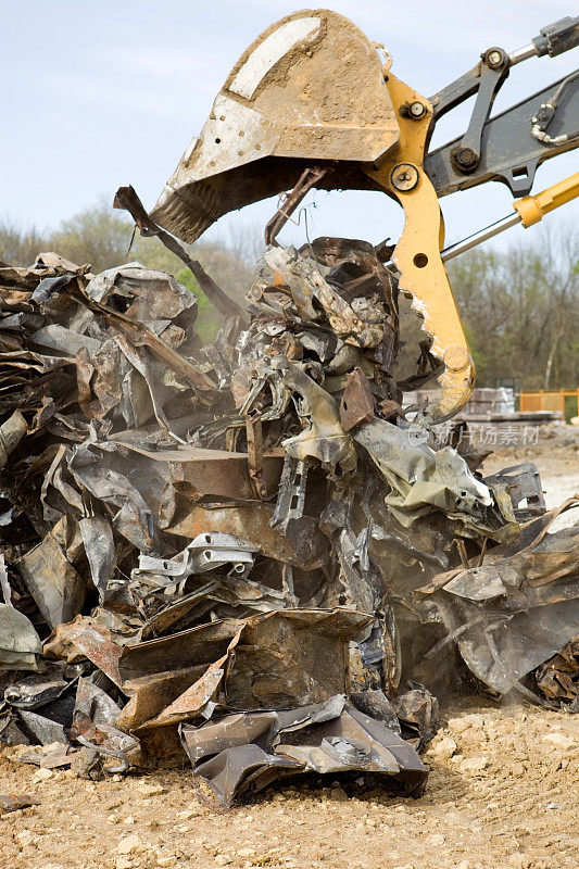 一场房屋火灾中，挖掘机铲斗倾倒废金属。