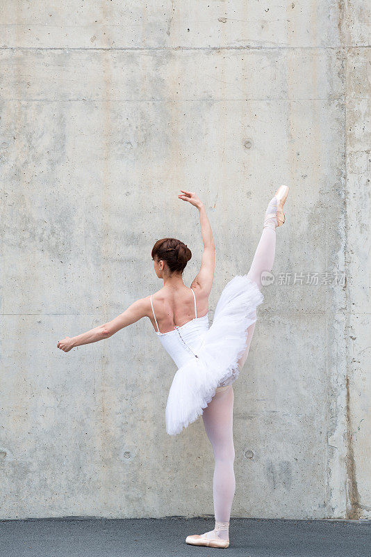 美丽的古典芭蕾舞者在混凝土前摆姿势