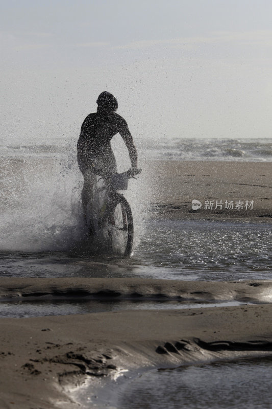一个骑自行车的人的剪影穿过海水