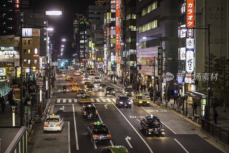 在日本东京市中心的霓虹夜市，上下班高峰期的通勤者