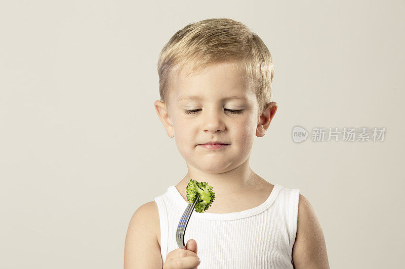 小男孩看着叉子上的西兰花