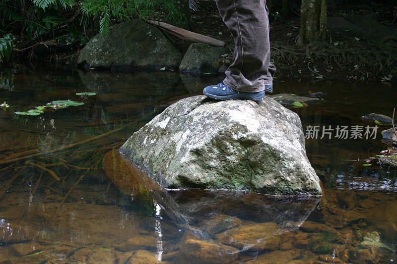 双脚站在溪流中的岩石上