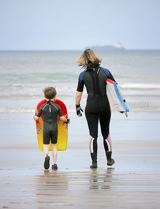 父母和孩子带着滑板走向大海