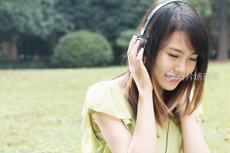 亚洲年轻女学生用平板电脑享受音乐。