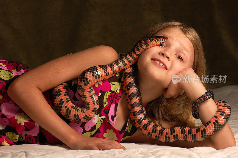 年轻的女孩紧张地抱着一条彩色的蛇。