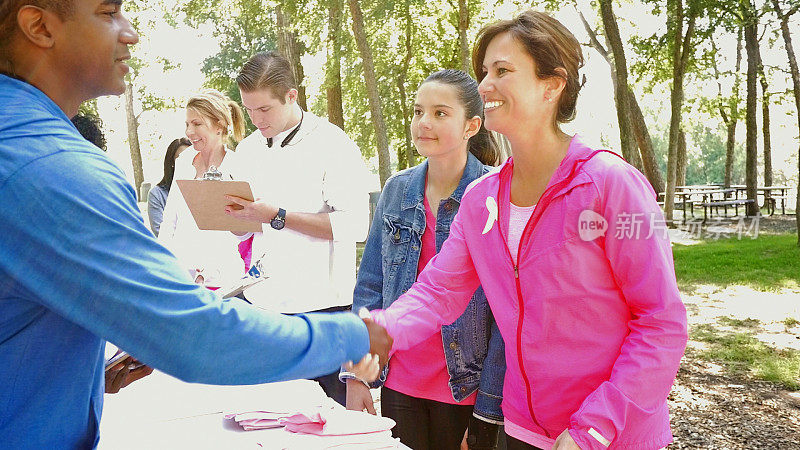 在乳腺癌意识竞赛中，志愿者与跑步者握手