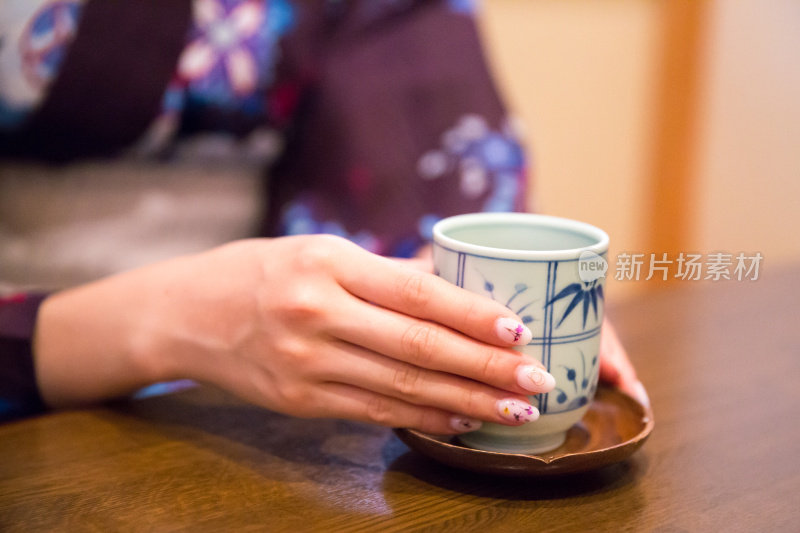 年轻的浴方女子拿着日本茶杯