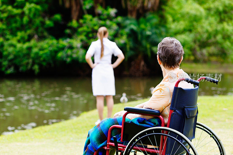 一个坐轮椅的女人看着她的护士看着湖面