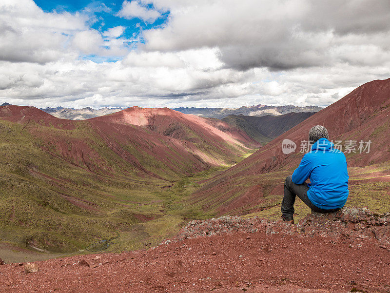 年轻的白人男性坐在享受风景与山丘，山脉，彩虹山，安第斯，秘鲁