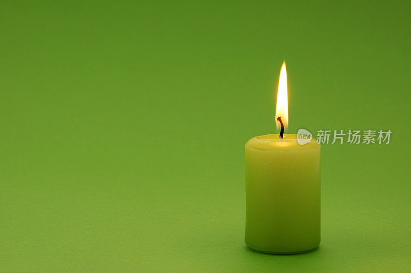 绿色背景上点燃的绿色蜡烛
