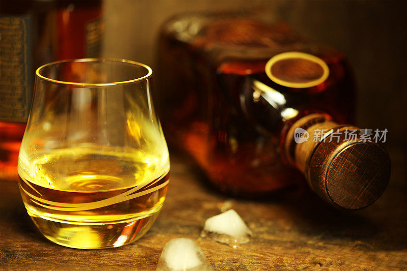 粗糙的木桌上放着苏格兰威士忌玻璃杯和酒瓶