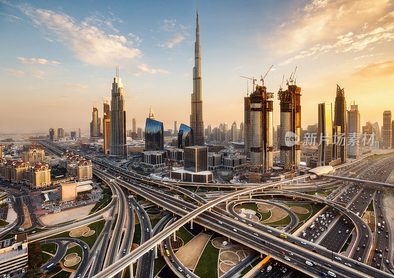 阿联酋迪拜壮观的天际线。一个大城市的未来主义现代建筑日落与一个大的高速公路交叉口。