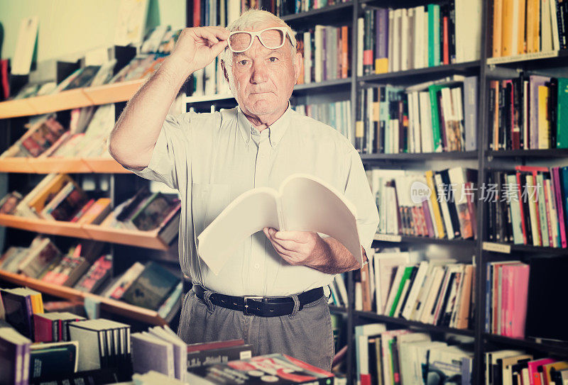 年长男性的肖像是寻找书的阅读