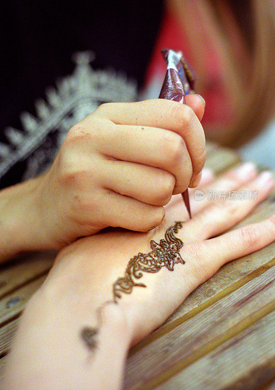 在女人手上画指甲花纹身。拍摄电影