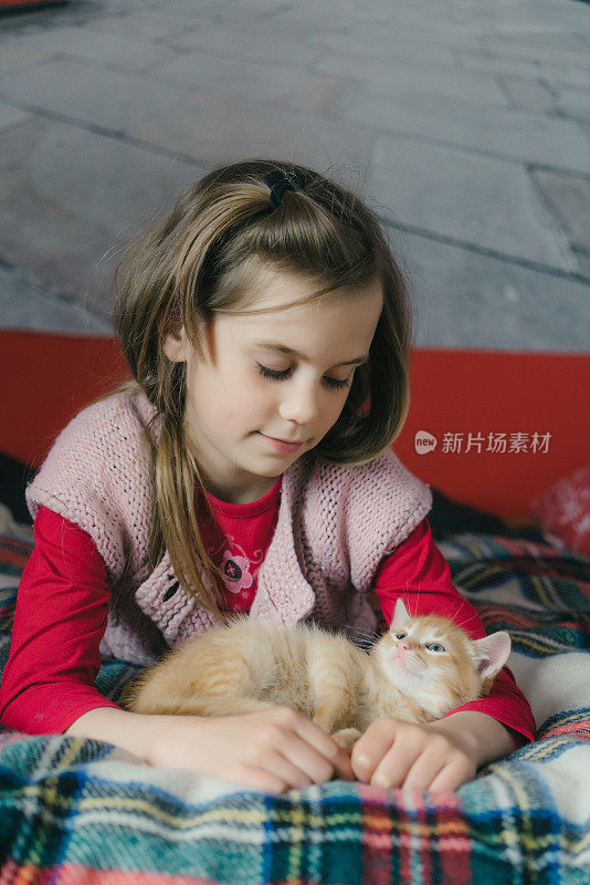 小女孩在床上和小猫玩