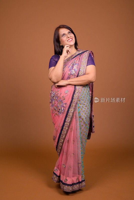 工作室拍摄的成年印度妇女穿着印度传统服装莎丽，以彩色背景为背景