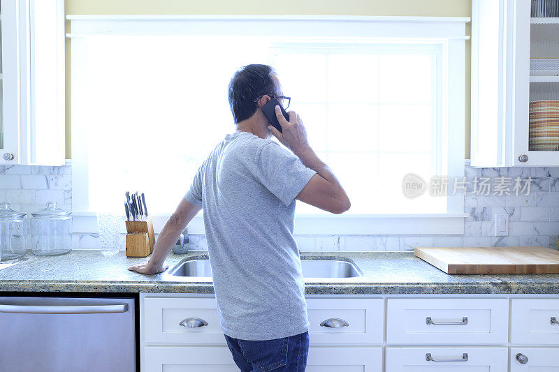 西班牙男子站在厨房里用手机交谈