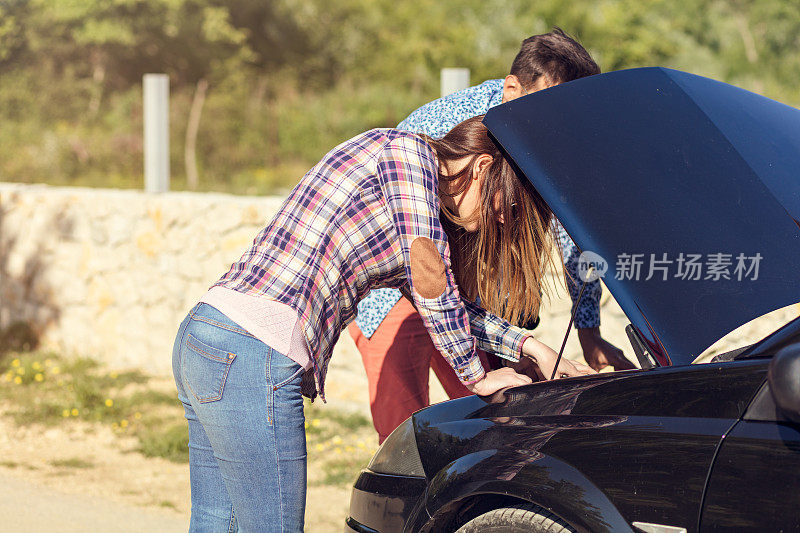 一对年轻夫妇在路边的汽车抛锚后