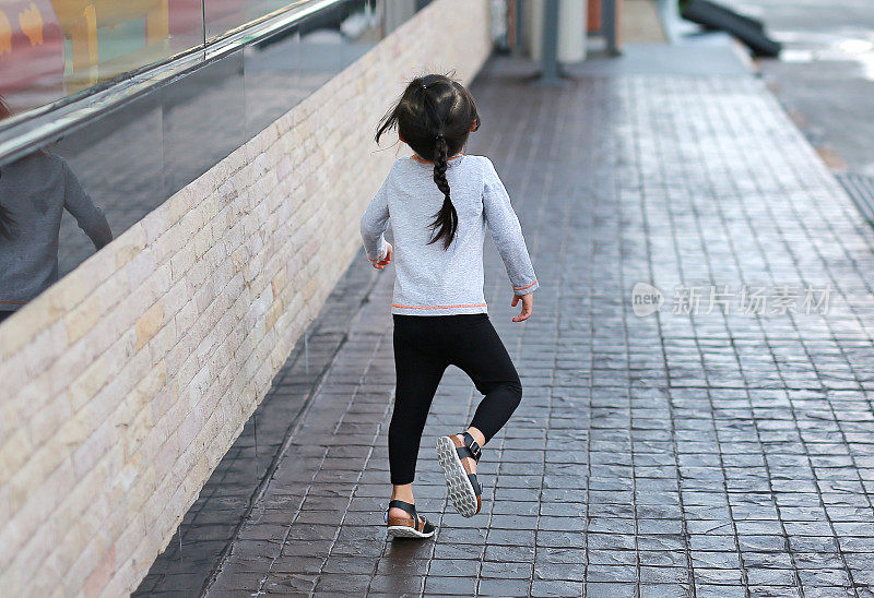 小女孩在人行道上奔跑的背影。