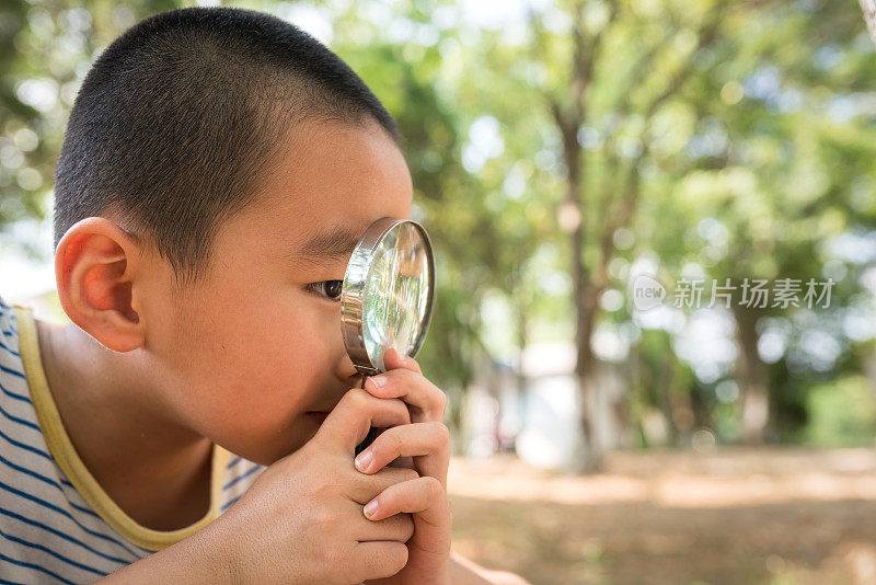 亚洲男孩拿着放大镜在大自然中寻找