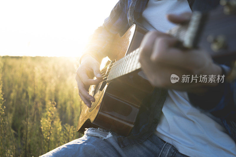 一个年轻人坐在草地上弹吉他