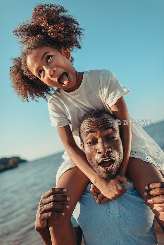非裔美国人父亲抱着女儿在海滩上