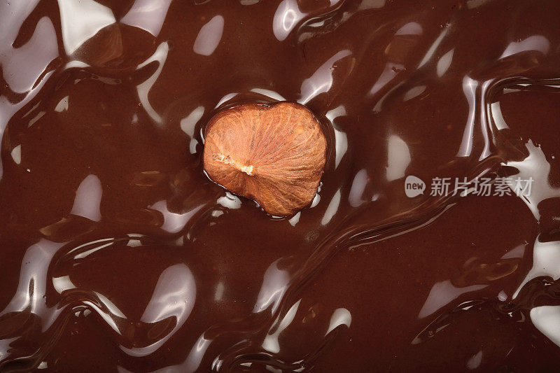 融化的巧克力漩涡与榛子作为背景特写