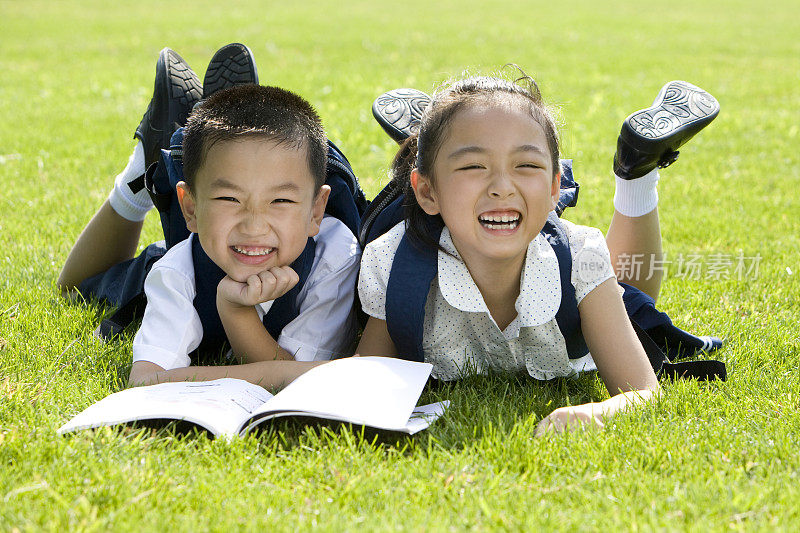 两个在草地上看书的小学生