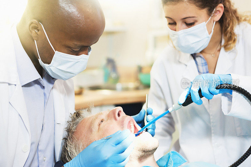 牙医和他的女助手在治疗男人的牙齿