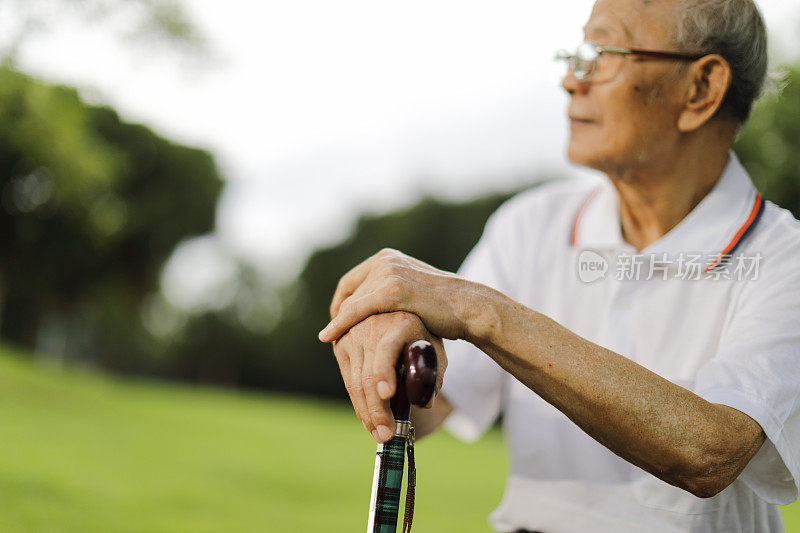 一个亚洲老人坐在公园里