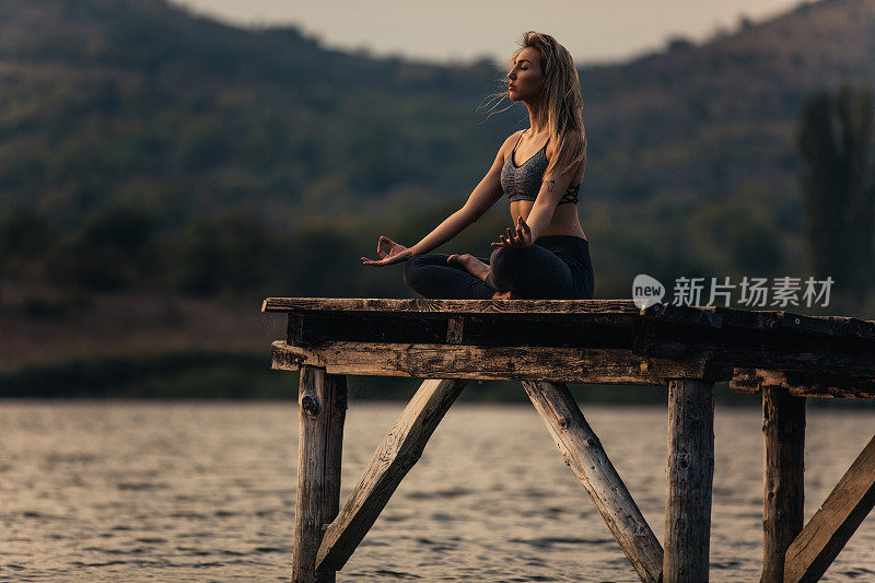 健康和运动的年轻女子在湖边做瑜伽