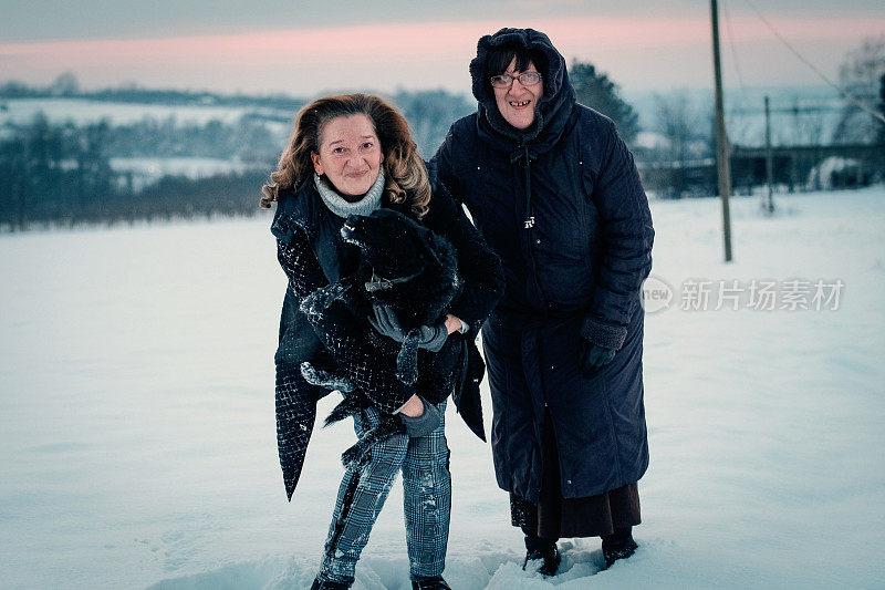 两个年长的女人在雪地上玩狗