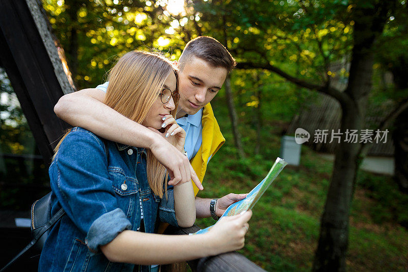 一对年轻夫妇在树林里的地图上找东西