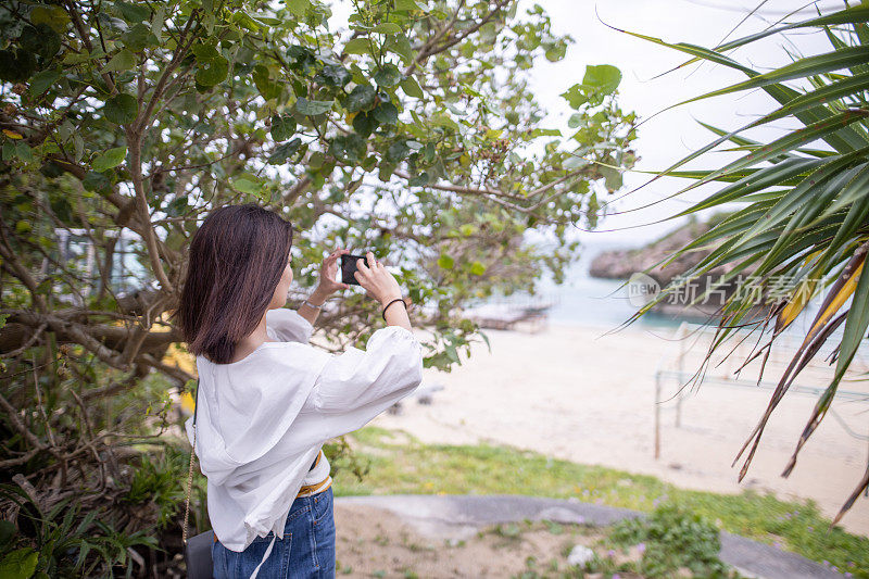 年轻女子拍摄美丽的度假海滩