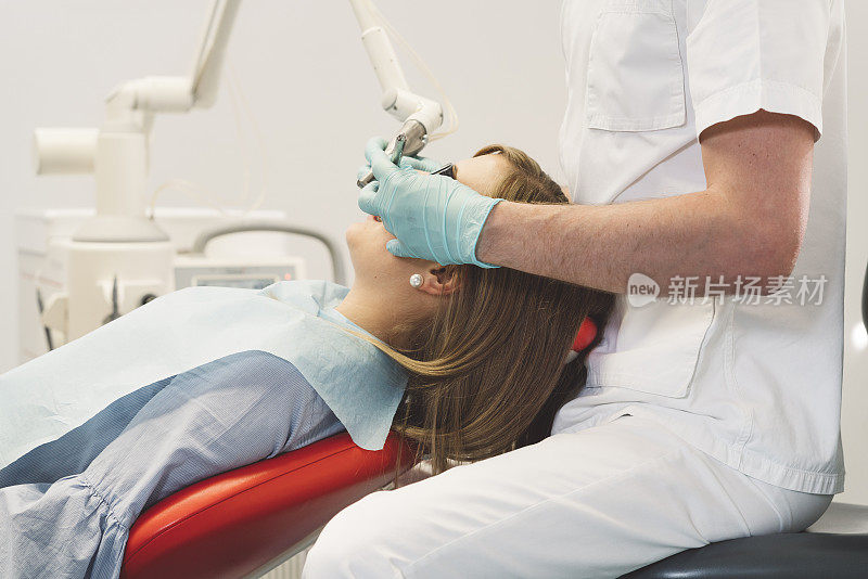 一个女人坐在牙医的椅子上，正在接受牙科治疗