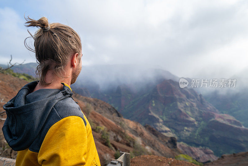 一名男子在夏威夷徒步旅行，从山顶俯瞰瀑布