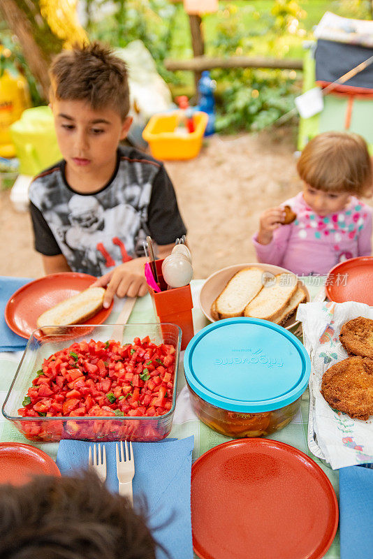 小男孩决定吃什么从各种新鲜的食物在户外午餐-库存照片