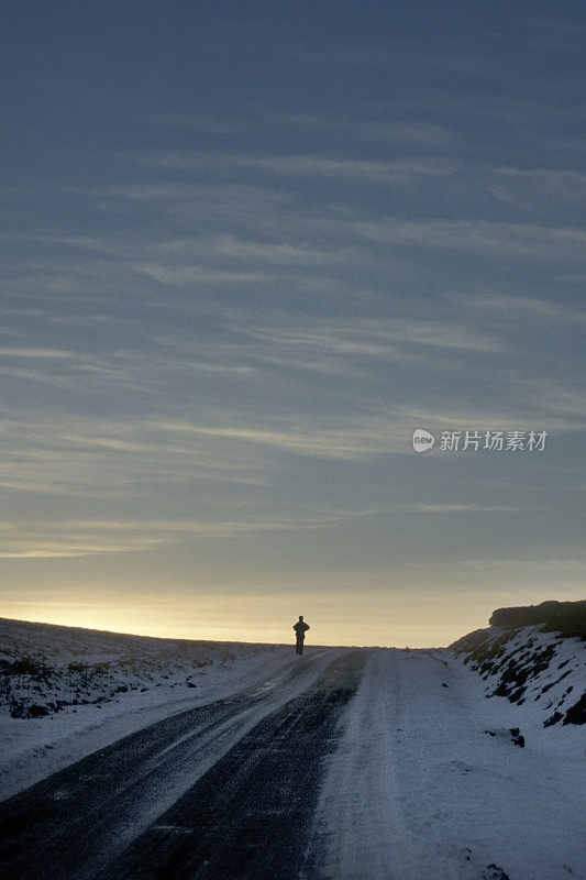 冬天，英国北约克郡，一个人在积雪覆盖的道路上行走或奔跑