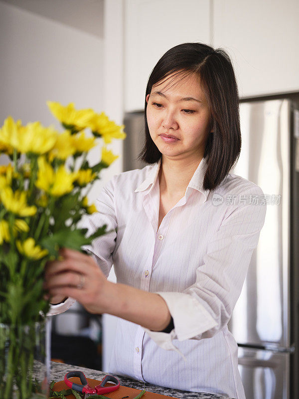 亚洲妇女在她的家里插花