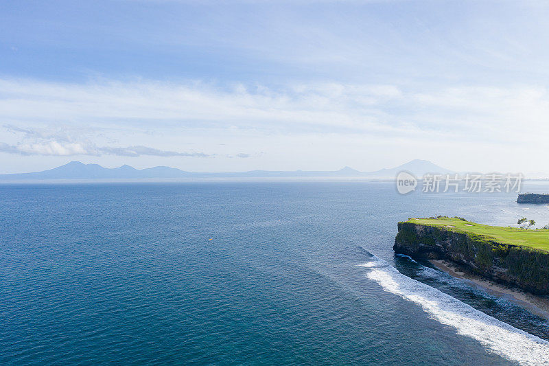 从上面看，巴厘岛的海岸――蓝色的海洋和岩石嶙峋的山丘，覆盖着热带植物。