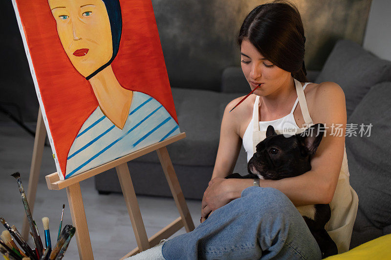 一个漂亮的女人在画画的时候抱着一只狗