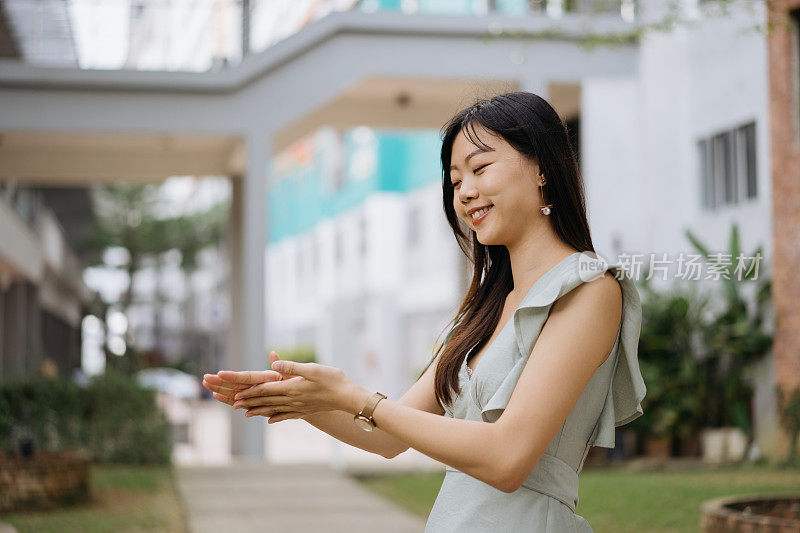 年轻的亚洲妇女用酒精洗手液消毒手，并互相搓手