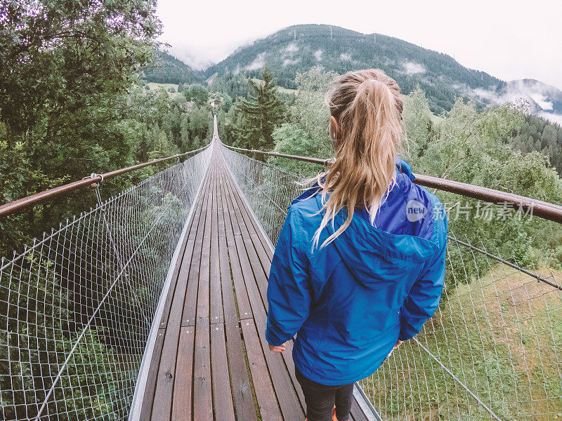 一名女子在瑞士松树谷的吊桥上行走
