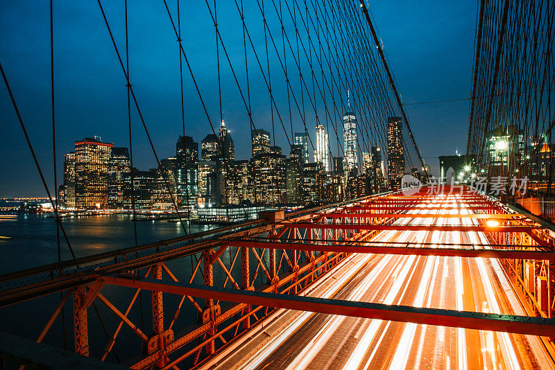 照亮夜晚的城市，纽约，美国，桥梁上的交通与照亮城市天际线的背景。